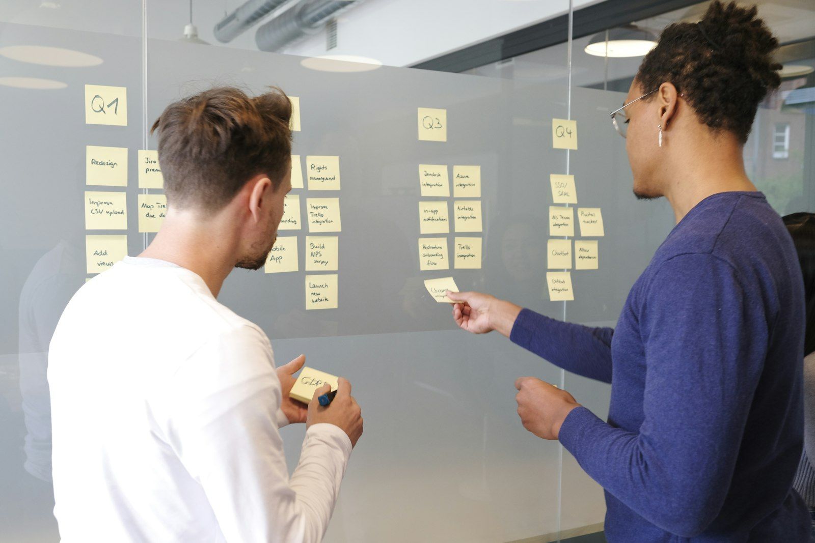 Team planning a project with sticky notes on a glass wall