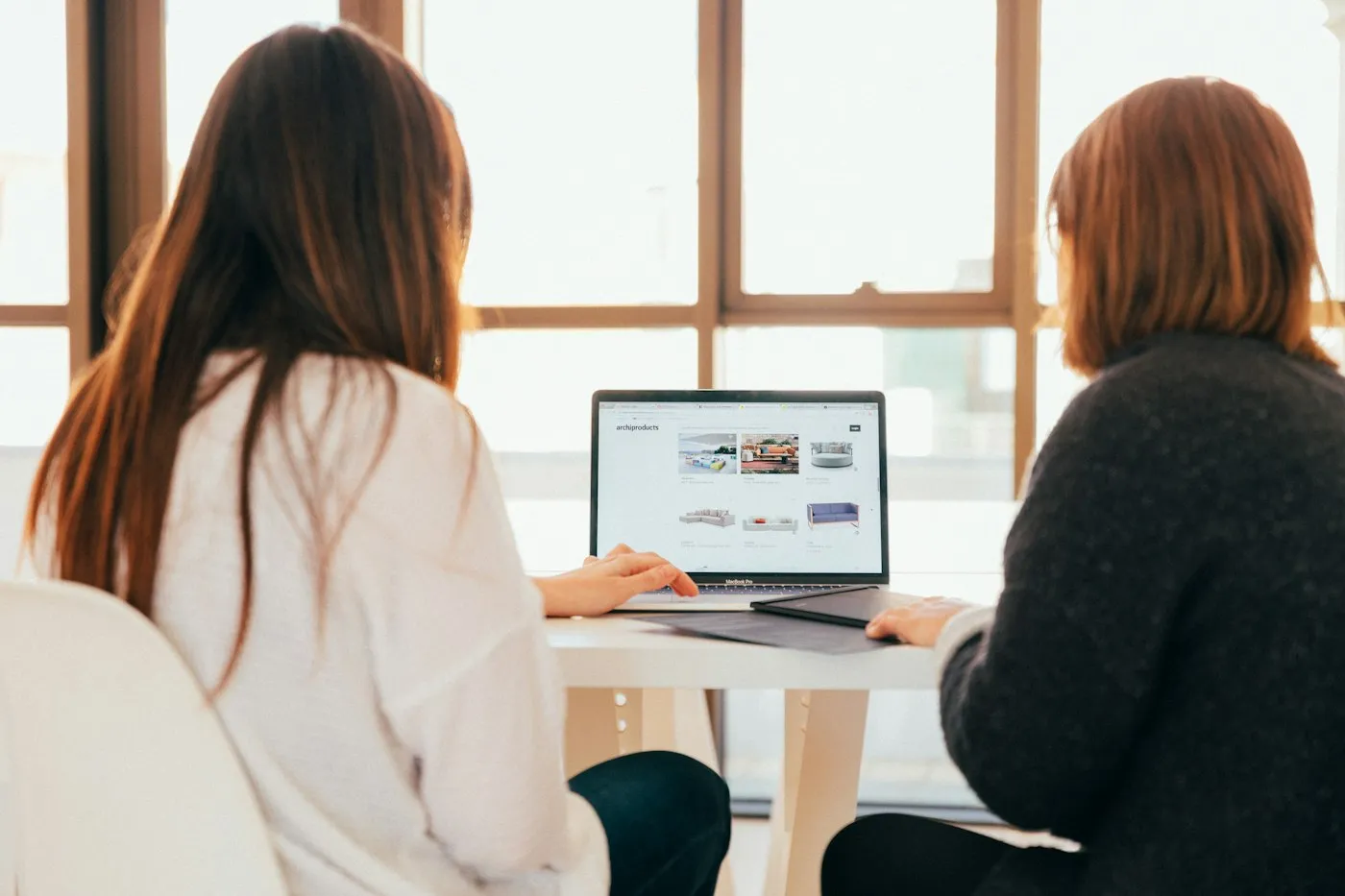 Two colleagues reviewing work together on a laptop