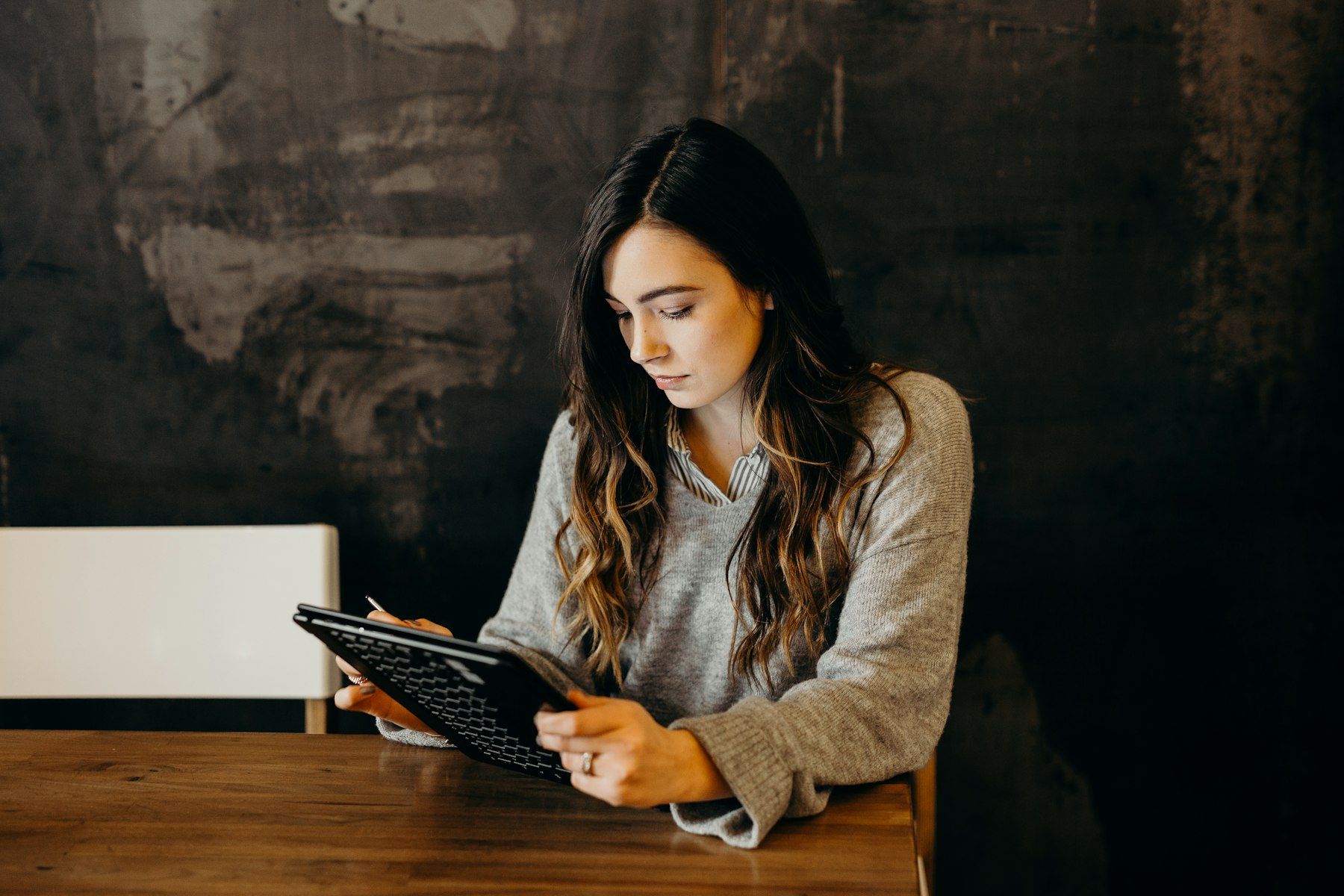 Professional reading on a tablet at a wooden table